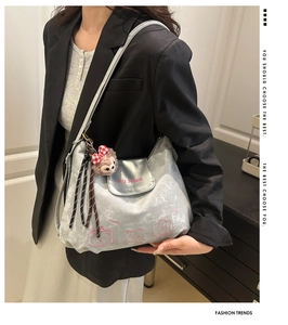 Silberne Metallic-Umhängetasche mit Bären-Stickerei und Plüsch-Anhänger am Model gezeigt