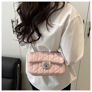 Detail of pink quilted crossbody bag with silver chain strap worn over the shoulder