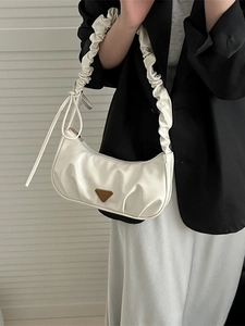 Elegante weiße Handtasche mit Falten-Design und klassischer Metall-Plakette im Fokus