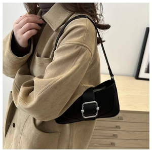 Gros plan du sac baguette en cuir noir avec une grande boucle métallique argentée