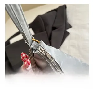 Detail der silbernen Nylontasche mit glattem Reißverschluss und Plüschbär-Anhänger