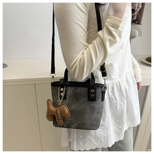 Detail of dark grey leather mini bucket bag with a cute puppy charm and gold chain