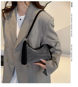 Detail einer schwarzen Achseltasche mit silbernen Strasssteinen am Model im grauen Blazer
