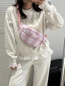 Pink and white checkered fanny pack with adjustable strap worn by a female model