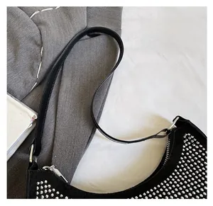 Detail einer schwarzen Hobo-Tasche mit Nieten auf Wildleder und schmalem Schultergurt