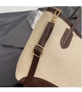Detail of adjustable shoulder strap with gold-tone hardware on beige bucket bag