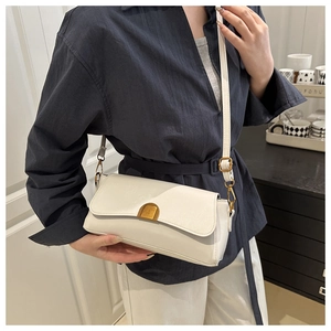 Détail d'un sac porté épaule crème avec fermoir en croissant doré et texture cuir raffinée