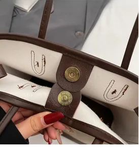 Detail of solid tote bag showing interior lining, brown leather trim and bronze magnetic clasp