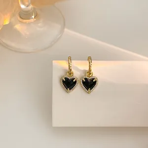 Vue détaillée de boucles d'oreilles cœur vintage en or avec pierres noires et cristaux