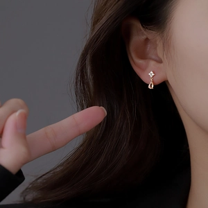 Close-up of elegant gold pear-shaped drop earrings with orange cubic zirconia on model