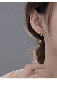 Close-up of champagne teardrop zircon earring on model with silver base and white stones