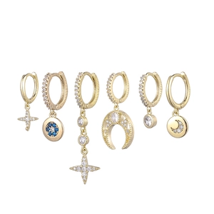 Macro detail of 18K gold star and moon earrings set featuring sparkling zircon stones