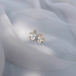 Detail of blue and white enamel flower earrings with pearls on silk fabric