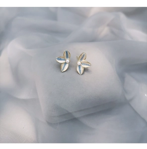 Close-up of blue and white enamel flower earrings with a small pearl in the center