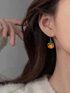 Close-up of S925 silver persimmon earrings with orange glass charm on a model's ear