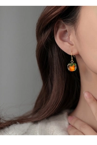 Detail of persimmon shaped 925 silver needle earrings on model with orange crystal