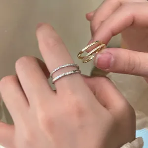 Detail shot of silver rope twist ring and gold double layer crisscross ring on hand