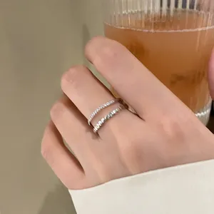 Detail of layered silver ring featuring textured wave and brushed bands in a sleek design