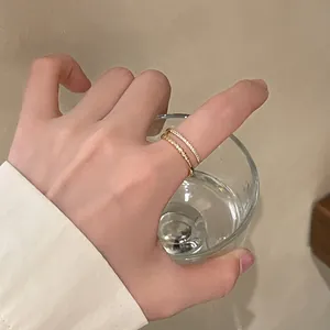 Detail of elegant gold beaded ring and thin zircon band stacked on model's index finger