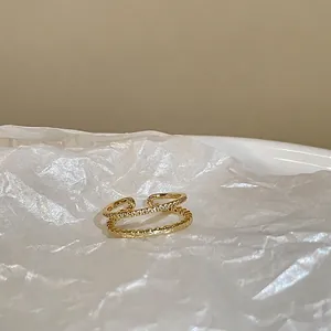 Macro detail of gold double-layered open ring with sparkling white zircon inlay