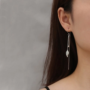Detailed view of S925 silver tassel earrings featuring hollow leaf pendant on model