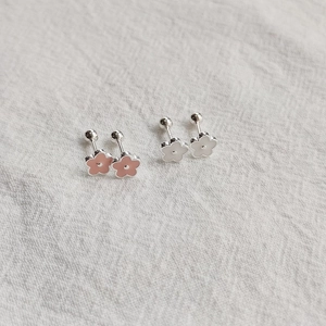 Detailed view of floral enamel stud earrings with screw-back closures in pink and white