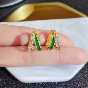 Detail of gold-plated hoop earrings with green enamel and sparkling zircon inlay