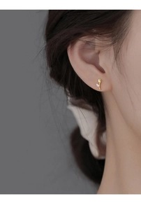 Macro view of gold tulip stud earrings with sparkling cubic zirconia on a model