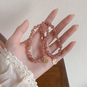 Armband aus rosa Erdbeerkristall mit goldenen Fu- und Cai-Glücksbringern