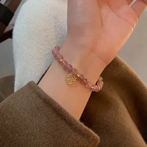 Detailaufnahme des rosa Kristallperlenarmbands mit goldenem Fu-Anhänger für Glück