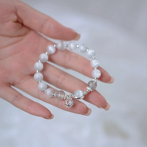 Close-up of cat eye stone beaded bracelet with hollow lantern pendant on a wrist