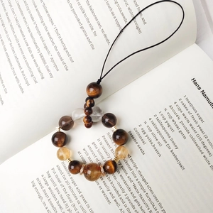 Golden tiger eye and citrine beaded phone charm strap on a vintage open book background