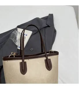 Detail of soft beige tote bag with brown handles and high-quality gold hardware