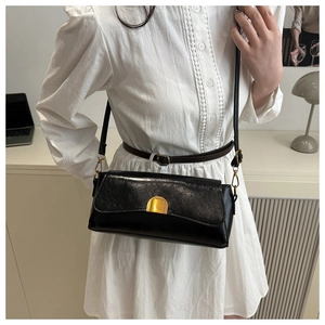 Détail du sac baguette noir avec fermoir doré rectangulaire et bandoulière chic en cuir