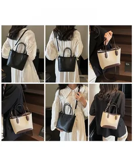 Detail view of large tote bags in matte black leather and beige canvas with leather trim