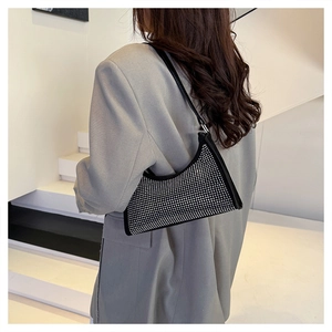 Detailaufnahme einer funkelnden silbernen Strass-Hobo-Tasche an der Schulter des Models