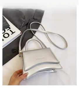Détail du sac argenté avec rabat asymétrique et bandoulière réglable