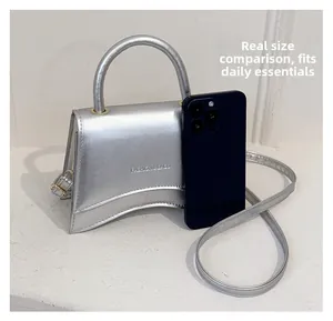 Comparaison de taille du mini sac argenté avec smartphone montrant sa capacité compacte