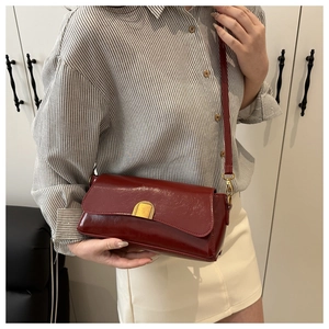 Gros plan détaillé d'un sac bandoulière en cuir verni bordeaux avec fermoir doré