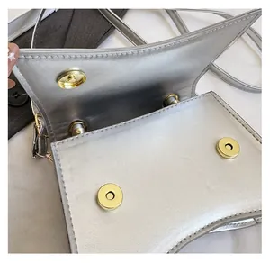 Vue détaillée de dessus du sac à main argenté avec double fermeture à bouton magnétique
