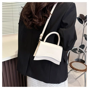 Détail du sac bandoulière en cuir blanc avec base ondulée et imprimé de lettres