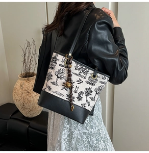 Detail of canvas tote bag with ink landscape print, leather trim and woven tassel charm