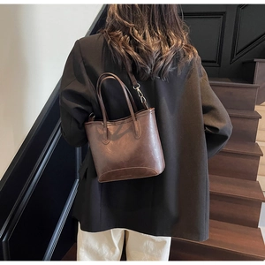 Detail of dark brown vintage leather tote bag worn by a model in a luxury setting