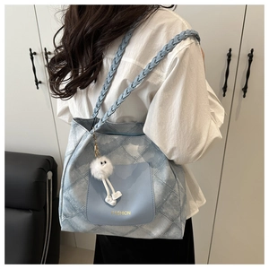 Dettaglio della borsa tote in denim azzurro con tracolla intrecciata e ciondolo