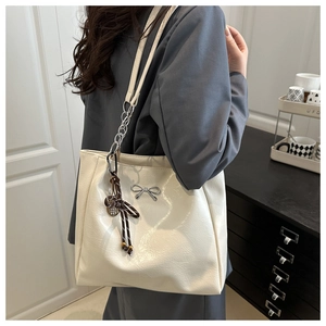Close-up of cream white tote bag featuring silver bow buckle and elegant ribbon detail