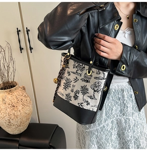 Detail of a canvas tote bag with landscape print and leather trim on a model
