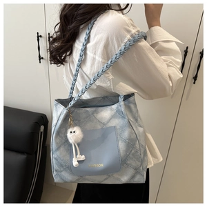 Dettaglio della borsa tote in denim blu con manici intrecciati e tasca frontale alla moda