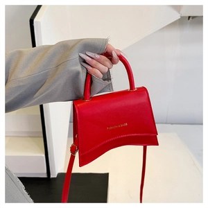 Détail du sac rouge avec une base incurvée unique et des lettres dorées de logo fashion