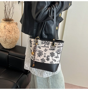 Detail of vintage style tote bag with floral patterns and leather strap on a sofa