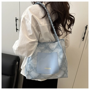 Detail of blue quilted denim tote bag with fashion pocket and woven rope handles